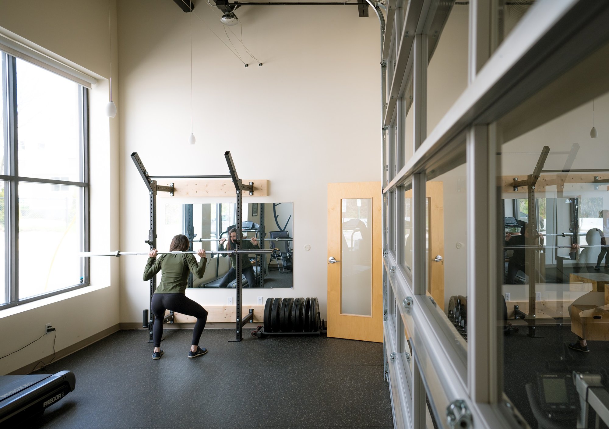 Person squatting a barbell in a squat rack in the Equipment Room at Steady State.