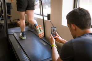 A physical therapist analyzing a runner's gait on a treadmill with gait analysis software.