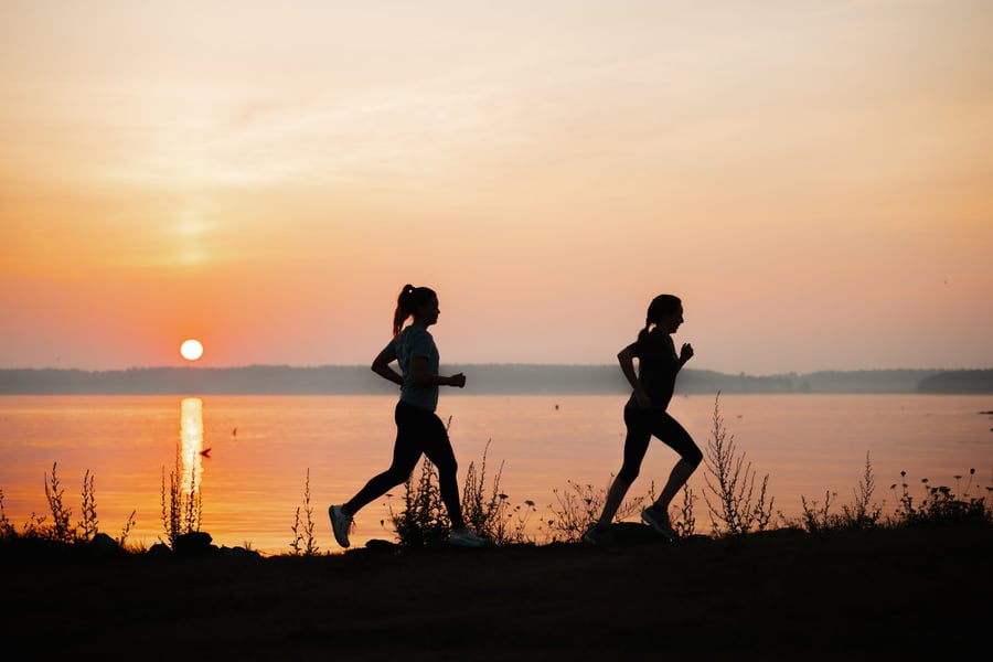 Two women running together at sunrise along the water in Portland, Maine.