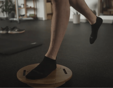 A runner balancing on a Moboboard to train their foot muscles.