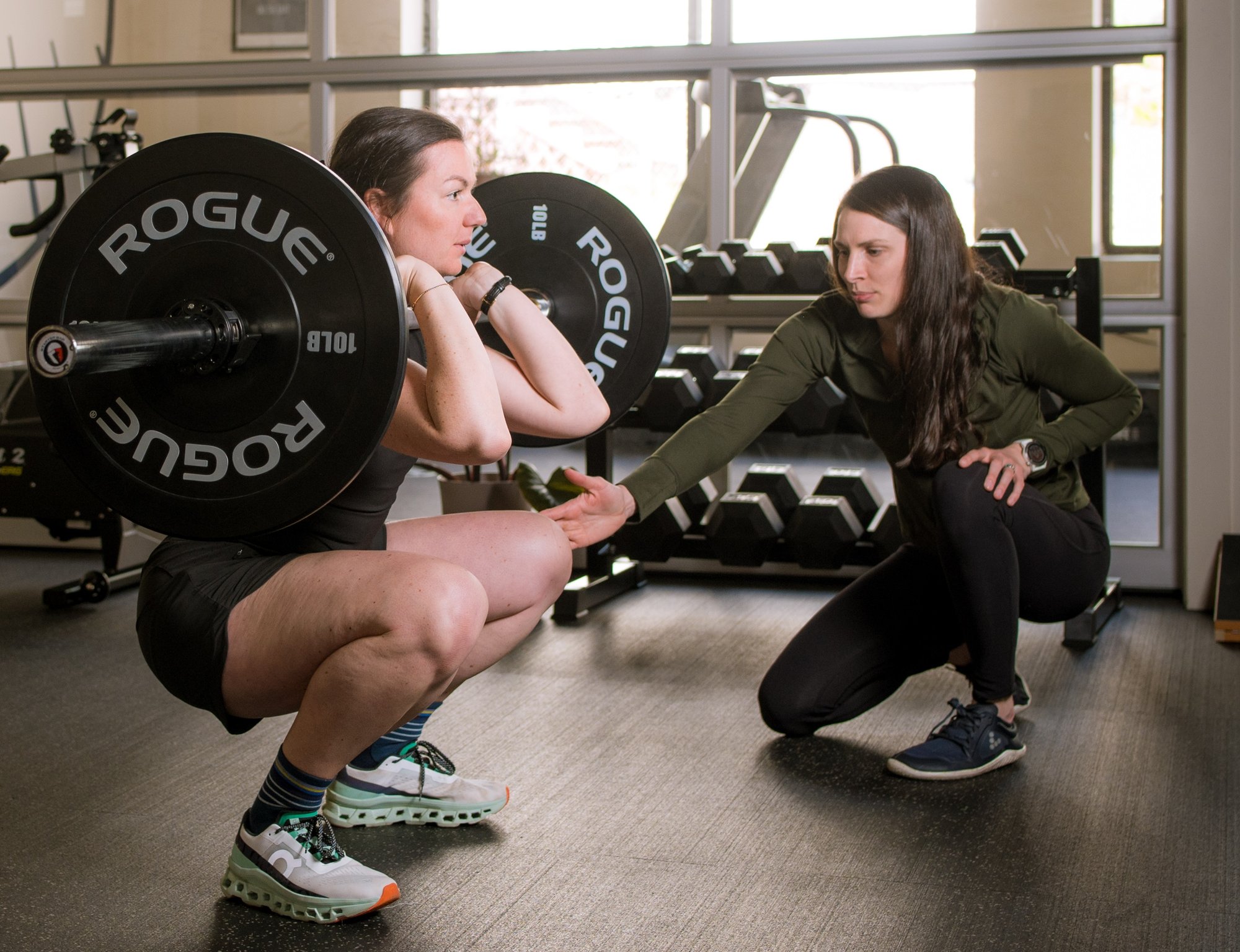 A Portland Maine Physical Therapist helping a runner with her squat form. 