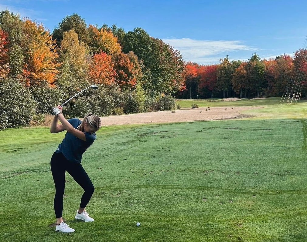 A golfer swinging a golf club on a fairway in Maine.