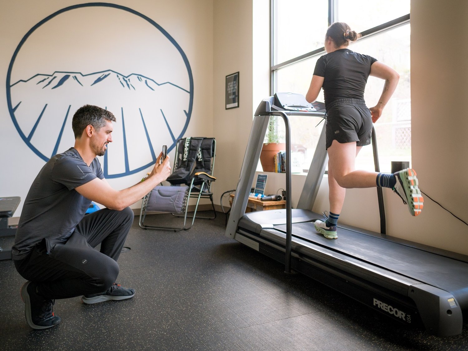 A Steady State physical therapist filming a runner's gait on the treadmill
